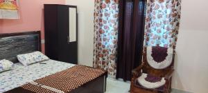 a bedroom with a bed and a chair with curtains at Guru Kripa Guest House ( Home Stay ) in Ayodhya