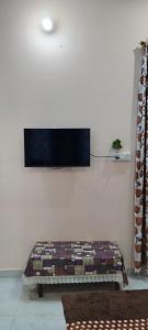 a room with a couch with a tv on the wall at Guru Kripa Guest House ( Home Stay ) in Ayodhya
