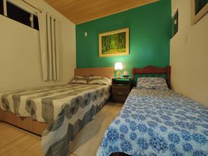 Dos camas en una habitación con paredes verdes. en Casa 200 Arraial, en Arraial do Cabo