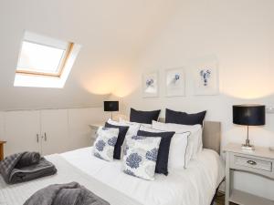 a bedroom with a white bed with blue and white pillows at Ty Glan y Mor - Pwllheli in Pwllheli