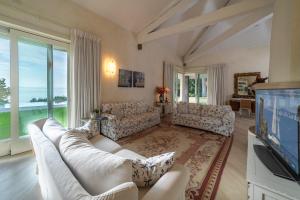 een woonkamer met witte meubels en een groot raam bij VILLA INFINITY - Regarda Travel in Bardolino