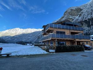 um grande edifício com montanhas cobertas de neve ao fundo em Chalet Chardonnay em Kaunertal