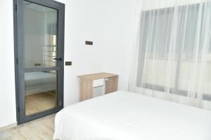 a bedroom with a white bed and a mirror at Stylish 3-Bedroom Flat in Kenitra Center Ville with Parking & Comfort in Kenitra