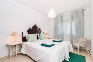 a white bedroom with a large bed with green pillows at Sea Side Apartment by SIDE VILLAS in Armação de Pêra