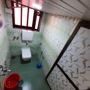 een kleine badkamer met een toilet en een raam bij Ashirvad cottage in Alībāg