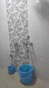 een badkamer met een douche en een blauwe emmer bij Ashirvad cottage in Alībāg