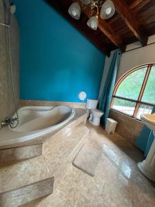 a bathroom with a tub and a toilet and a blue wall at Siwõ Art Guesthouse in Ocotal