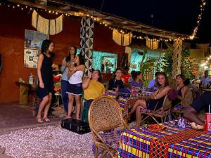 um grupo de pessoas sentadas em mesas em um restaurante em MANGO LODGE em Bubaque