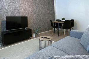 uma sala de estar com um sofá, uma televisão e uma mesa em City Apartment Haapaniemenkatu em Kuopio