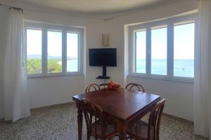 a dining room with a table and chairs and a television at Villa Federigo - Monte Argentario in Monte Argentario