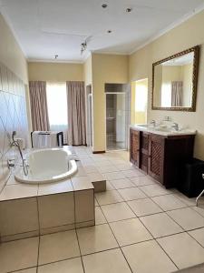 a large bathroom with a tub and a mirror at Limpopo Guest Manor in Polokwane