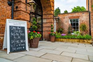 un cartel frente a un edificio de ladrillo con flores en Mytton and Mermaid - Brunning and Price en Shrewsbury