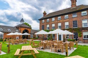 un restaurant avec des tables et des parasols en face d'un bâtiment dans l'établissement Mytton and Mermaid - Brunning and Price, à Shrewsbury