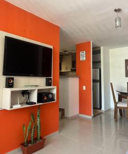 sala de estar con pared de color naranja y TV de pantalla plana en Casa Familiar en Armenia