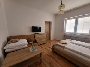 a bedroom with two beds and a tv and a table at Apartament pod Basztą in Muszyna