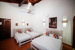 three beds in a room with white walls at Hotel La Casona Mompox in Mompós