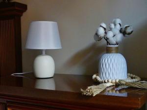 una mesa con una lámpara y un jarrón con flores. en SERVETTOHOME en Turín