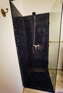 a shower with a black tiled wall at Riad Naya in Marrakech