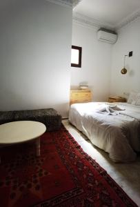 a bedroom with a bed and a table and a rug at Riad Naya in Marrakesh