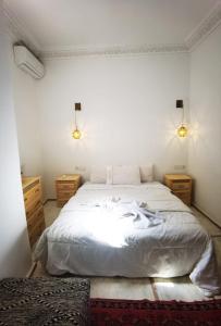 1 dormitorio con 1 cama blanca grande y 2 mesitas de noche en Riad Naya, en Marrakech