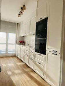 una cocina con armarios blancos y un aparato negro en Luminoso ático con terraza en Santander