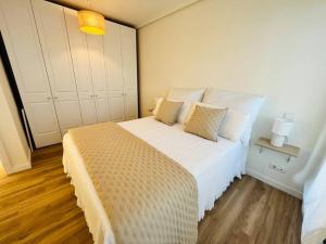Un dormitorio con una gran cama blanca con dos almohadas. en Luminoso ático con terraza, en Santander
