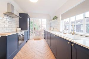 a large kitchen with blue cabinets and a large window at Hamlet's Nest in Stratford-upon-Avon