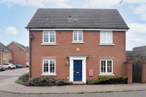 uma casa de tijolos vermelhos com uma porta azul em Partridge Close em Stowmarket