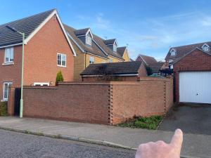 uma mão apontando para uma cerca de tijolos na frente das casas em Partridge Close em Stowmarket