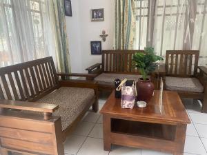 a room with three wooden chairs and a table with a plant at Wijaya homestay in Subang