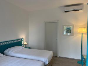 een slaapkamer met 2 bedden en een lamp en een deur bij Hotel Baia Delle Sirene in Taormina