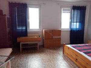 a bedroom with a bed and a desk and two windows at Pohodlná bytovka in Prešov