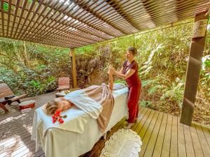 a woman is making a bed on a deck with a girl at Pousada Vila do Bosque in Bombinhas