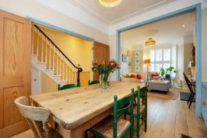 a dining room with a wooden table and green chairs at Veeve - Sunshine Joy in London