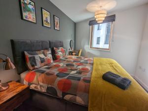 ein Schlafzimmer mit einem Bett mit einer Bettdecke und einem Fenster in der Unterkunft Beautiful Modern Coventry City Centre Apartment in Coventry