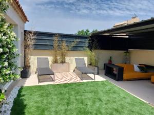 a patio with two chairs and a couch and grass at Maison entière Redessan in Redessan