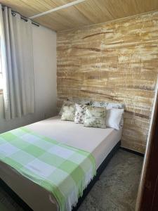 1 dormitorio con 1 cama con pared de madera en residencia bem viver, en Arraial do Cabo