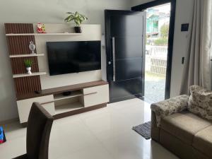 a living room with a tv and a couch at Casa de praia in Camboriú