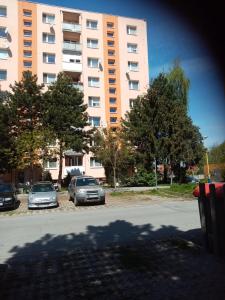 dos autos estacionados en un estacionamiento frente a un edificio en Pohodlná bytovka, en Prešov