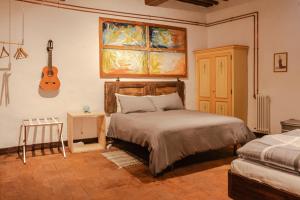 ein Schlafzimmer mit einem Bett und einer Gitarre an der Wand in der Unterkunft Il Convento in Sansepolcro