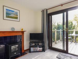 a living room with a fireplace and a balcony at Hazel Cottage in Bude