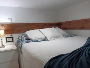 Schlafzimmer mit einem weißen Bett mit einem Kopfteil aus Holz in der Unterkunft El Pozo-Villalobos Suite in Madrid