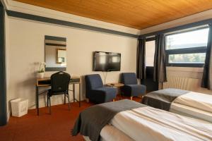 ein Hotelzimmer mit 2 Betten, einem Schreibtisch und einem TV in der Unterkunft Øiseth Hotell AS in Rendalen