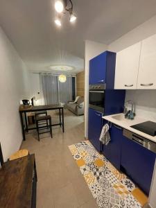 une cuisine avec des placards bleus et une table avec une salle à manger dans l'établissement Studio cosy vallée de Tarentaise, à Aime La Plagne