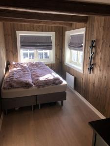 a bedroom with a bed and two windows at Stugu - Koselig hytte med sentral beliggenhet 