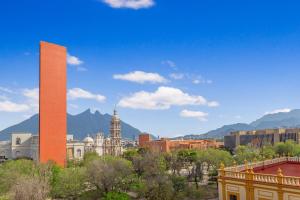 einen hohen Turm in einer Stadt mit Bergen im Hintergrund in der Unterkunft Hotel Monterrey Macroplaza in Monterrey