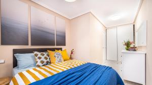 una camera da letto con un letto con cuscini blu e gialli di Apartamento a 3 min de la playa a Torrevieja