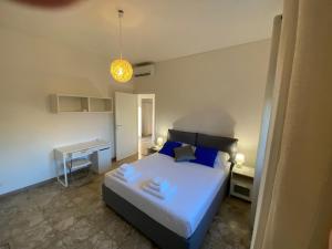 Schlafzimmer mit einem Bett mit blauen Kissen und einem Schreibtisch in der Unterkunft CASA BALU' in Rom