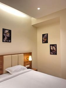 a bedroom with a bed and three pictures on the wall at Hotel Krystal in Sangli