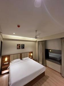 a bedroom with a large white bed and a tv at Hotel Krystal in Sāngli